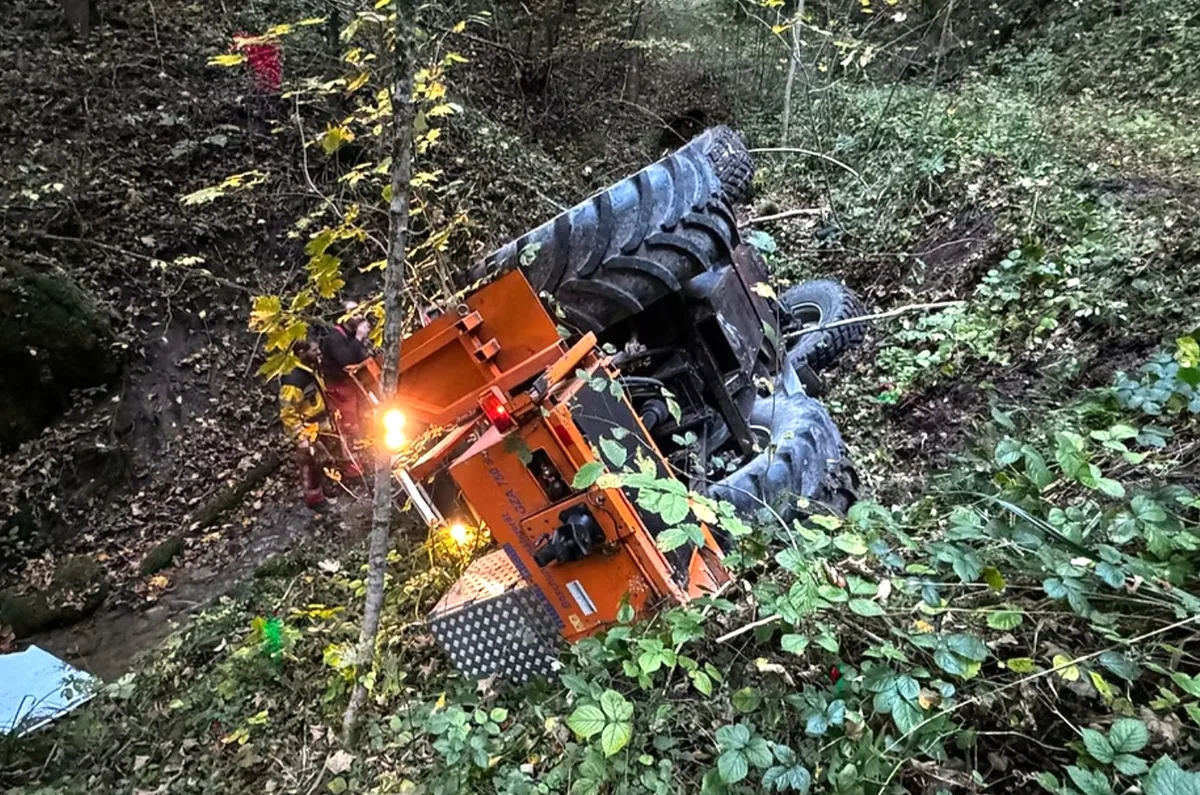 So kam der Traktor letztlich im Bach zu liegen. Man sieht einen Traktor, der auf seiner linken Seite in einem Bach liegt.