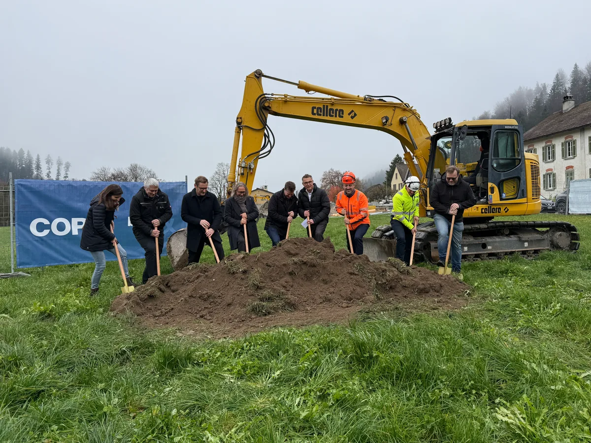 Mehrere Personen stehen auf einer Wiese und stechen jeweils mit einem Spaten in die Erde.