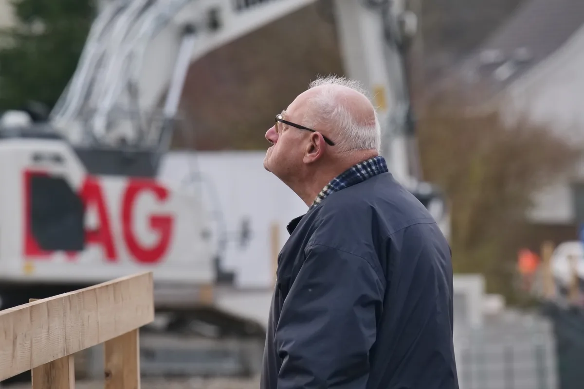 Ein Mann schaut staunend zu, wie eine Brücke mit einem Kran abgetragen wird.