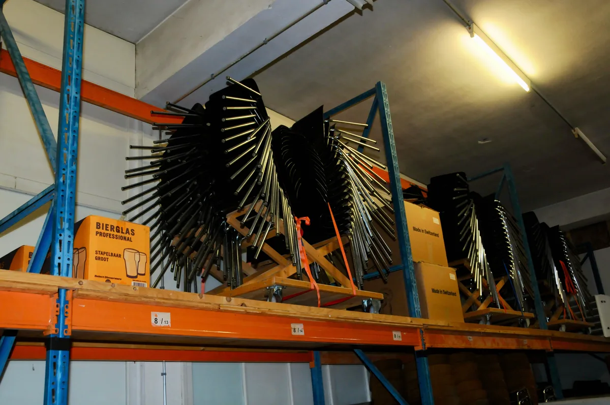 … die Gerätschaften müssen gestapelt, über- und hintereinander angeordnet werden … Man sieht gestapelte Stühle in einem Lagerraum, an die man fast nicht herankommt.