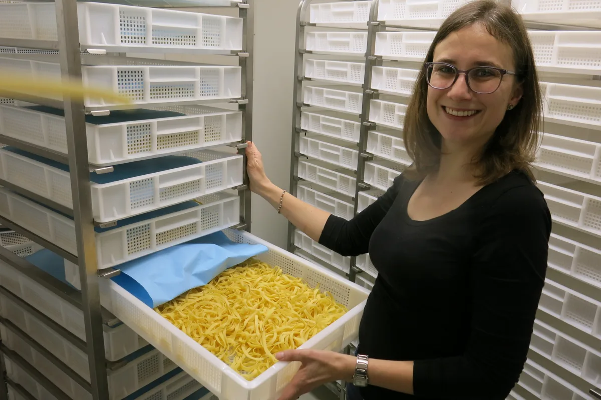 Eine Frau mit einer Kiste frischer Nudeln.