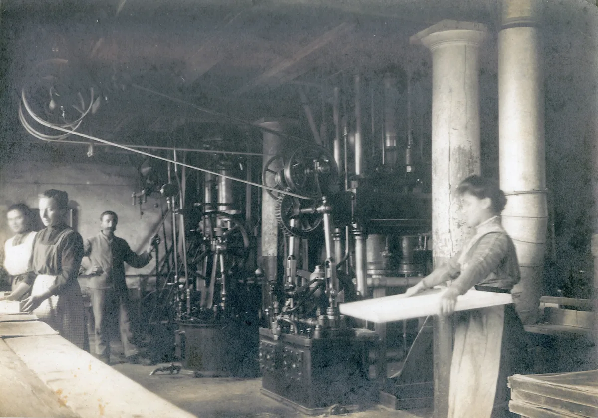 Mitarbeitende in der Fabrik. Man sieht ein altes Foto von Mitarbeitenden in einer Fabrik.