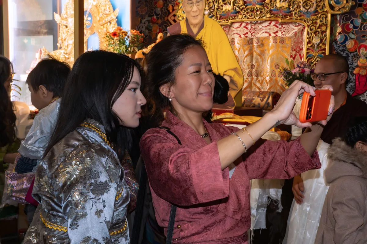 Man sieht zwei Frauen, die Fotos von Familien machen.