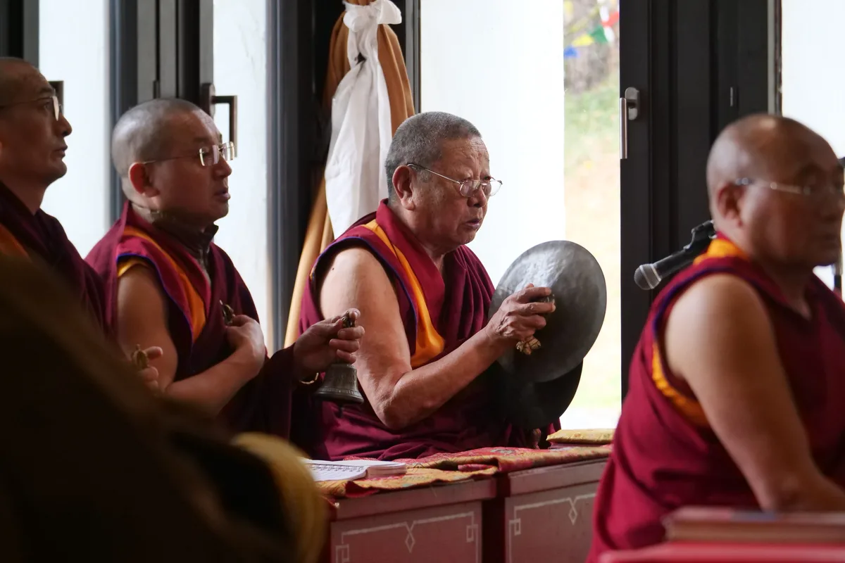 Man sieht Mönche, die mit tibetischen Instrumenten Musik machen.