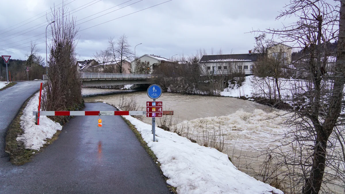 Bereits 2021 waren an der Brücke Sofortmassnahmen notwendig. Der Radweg wurde deshalb gesperrt. (Archiv) Man sieht einen gesperrten Radweg, der neben einem tosenden Fluss verläuft. Im Hintergrund ist eine Autobrücke erkennbar.