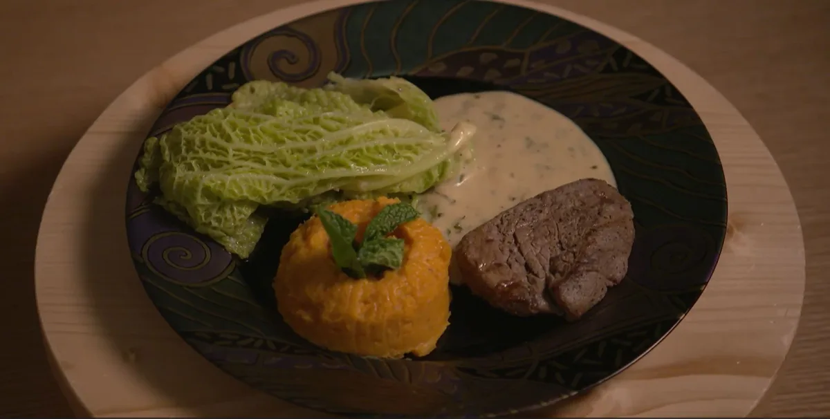Man sieht einen Teller mit Wirz, Süsskartoffelpüree und einem Rindsfilet an einer Sauce.