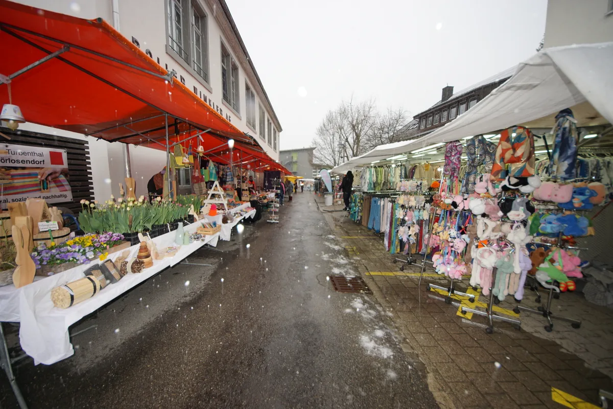 Man sieht eine Gasse an einem Markt mit Schneeflocken.