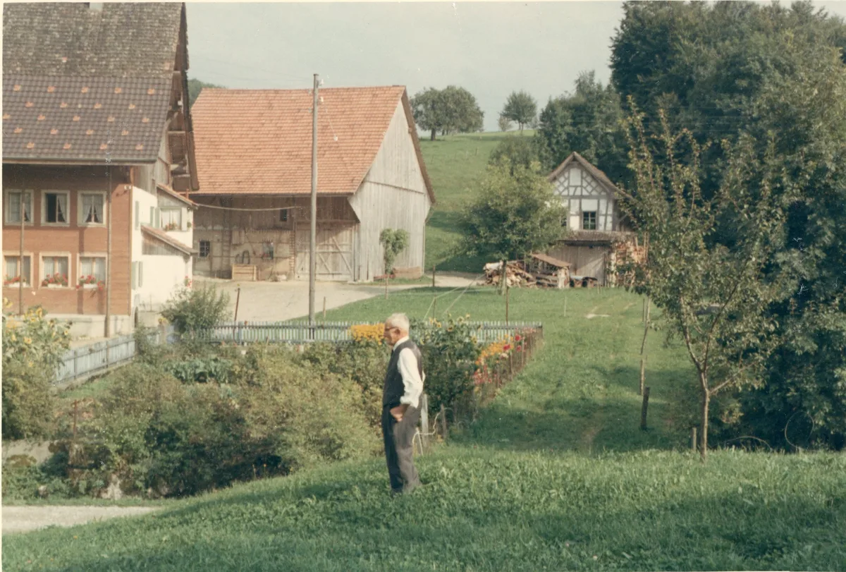 Fritz Bieri-Gafner vor der Mühle Schalchen, etwa 1970. Man sieht einen Hof aus mehreren Häusern, im Vordergrund steht ein Mann.