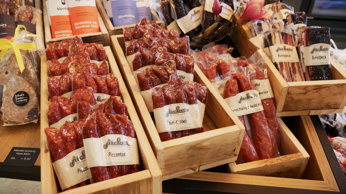 Vakuumierte Würste in Holzregalen.