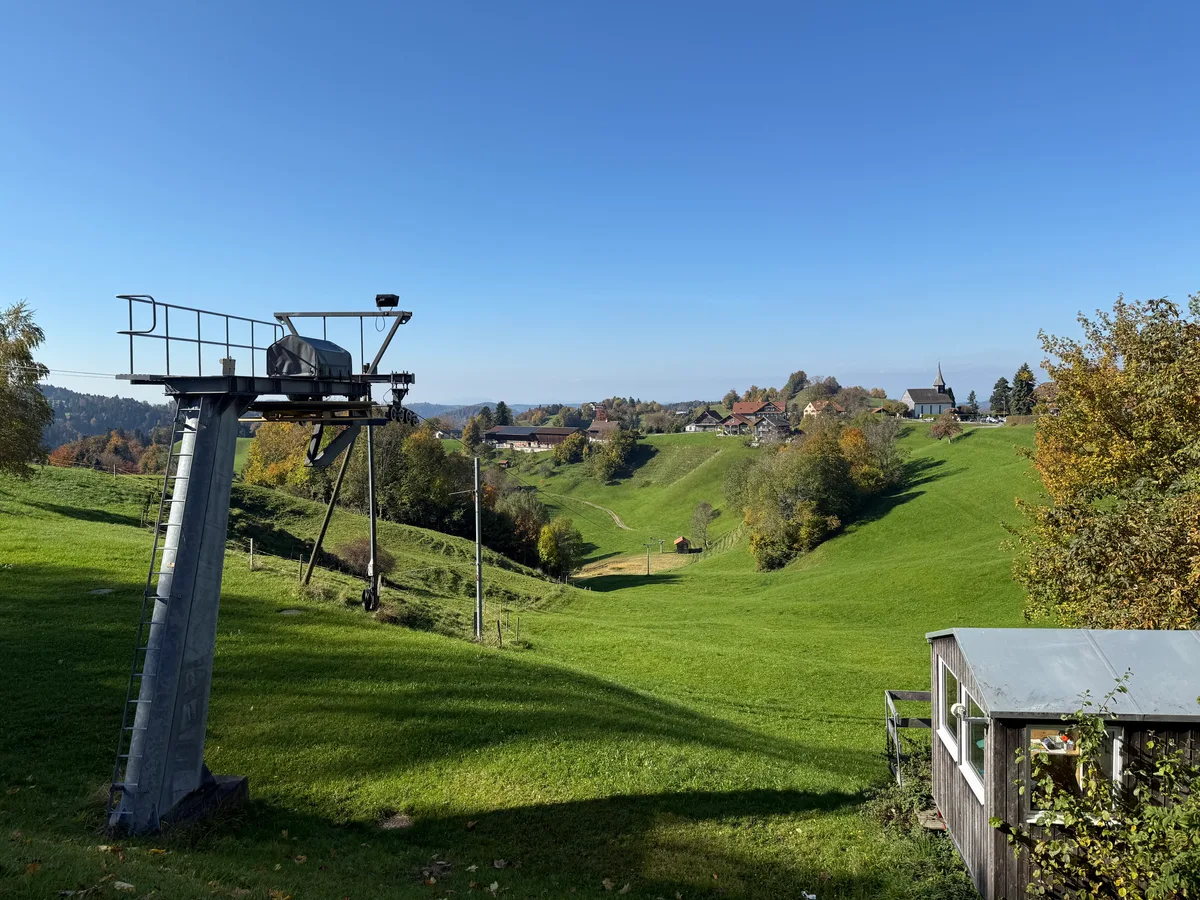 Man sieht einen Skilift auf einer grünen Wiese. 