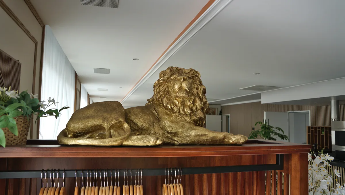 Löwenskulptur auf einem Holzkorpus.