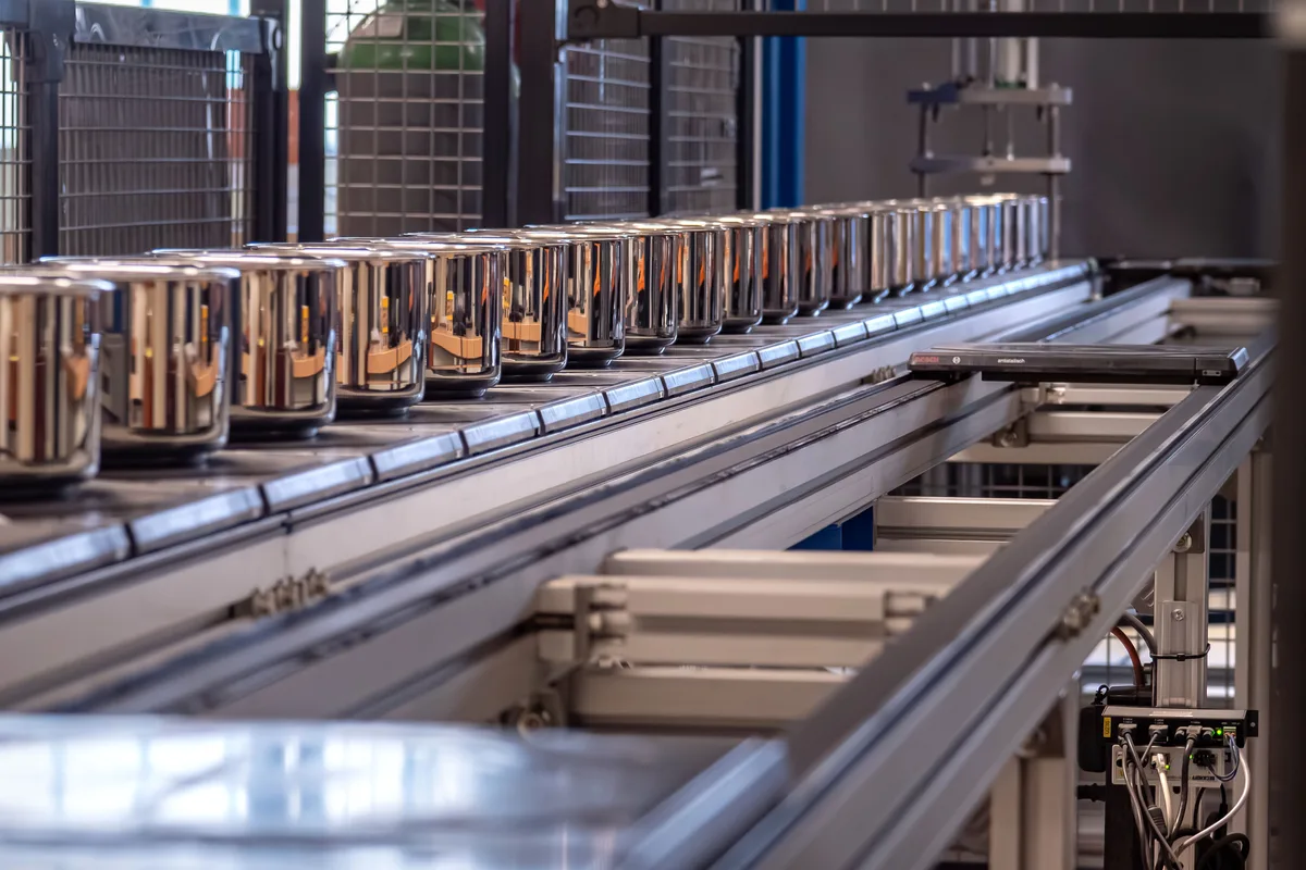 Blick in die Produktion von Kuhn Rikon: Knapp die Hälfte des Umsatzes erwirtschaftet das Unternehmen in der Schweiz. Blick in die Produktion von Kuhn Rikon am Hauptsitz in Rikon. Man sieht eine Produktionsstrasse mit silbern glänzenden Töpfen.