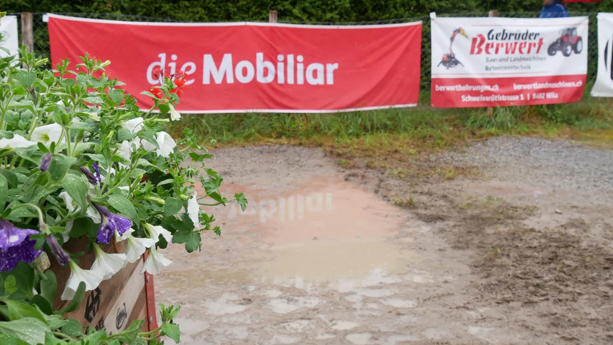 Man sieht Sponsorenbanden und eine Pfütze.