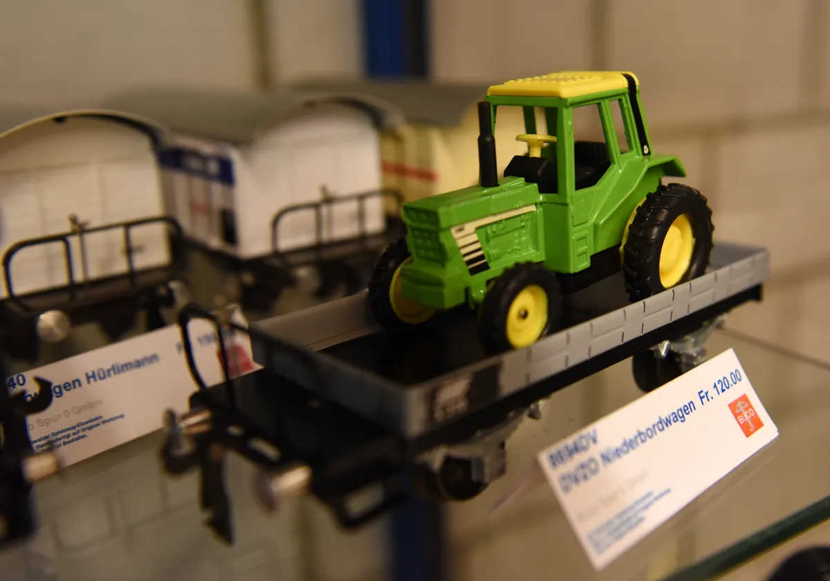 30 Serien hat die Firma seit 2011 auf den Markt gebracht. Man sieht einen Spielzeugtraktor auf einem Spielzeugeisenbahnwagen.
