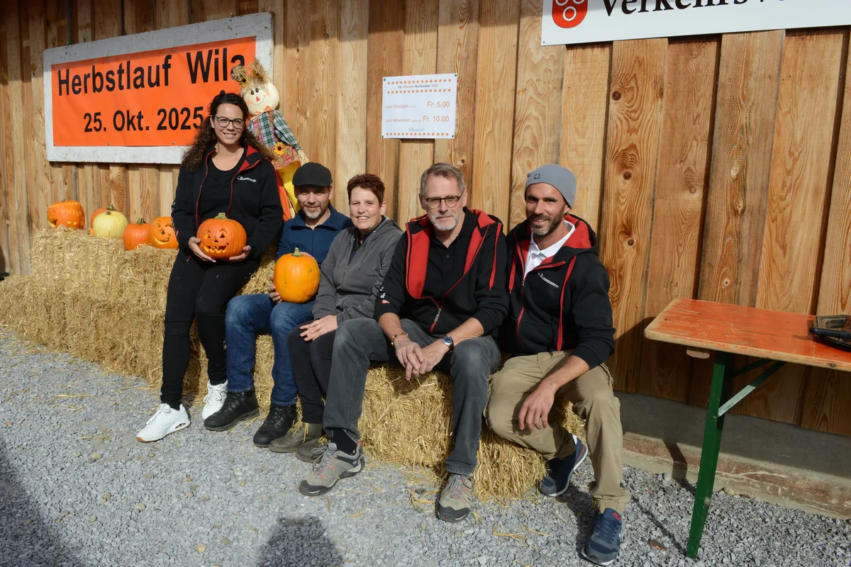 Man sieht fünf Leute, die auf Heuballen sitzen.