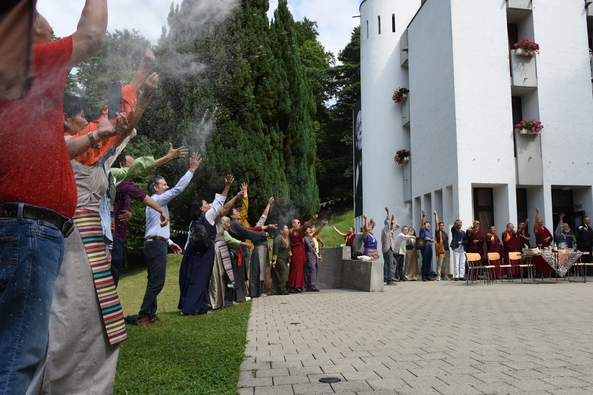 Am Ende der Gebetszeremonie warfen die Teilnehmenden eine Handvoll Mehl in die Luft. Die Einweihung des Fotobanners vom Dalai Lama am Tibet-Institut in Rikon.