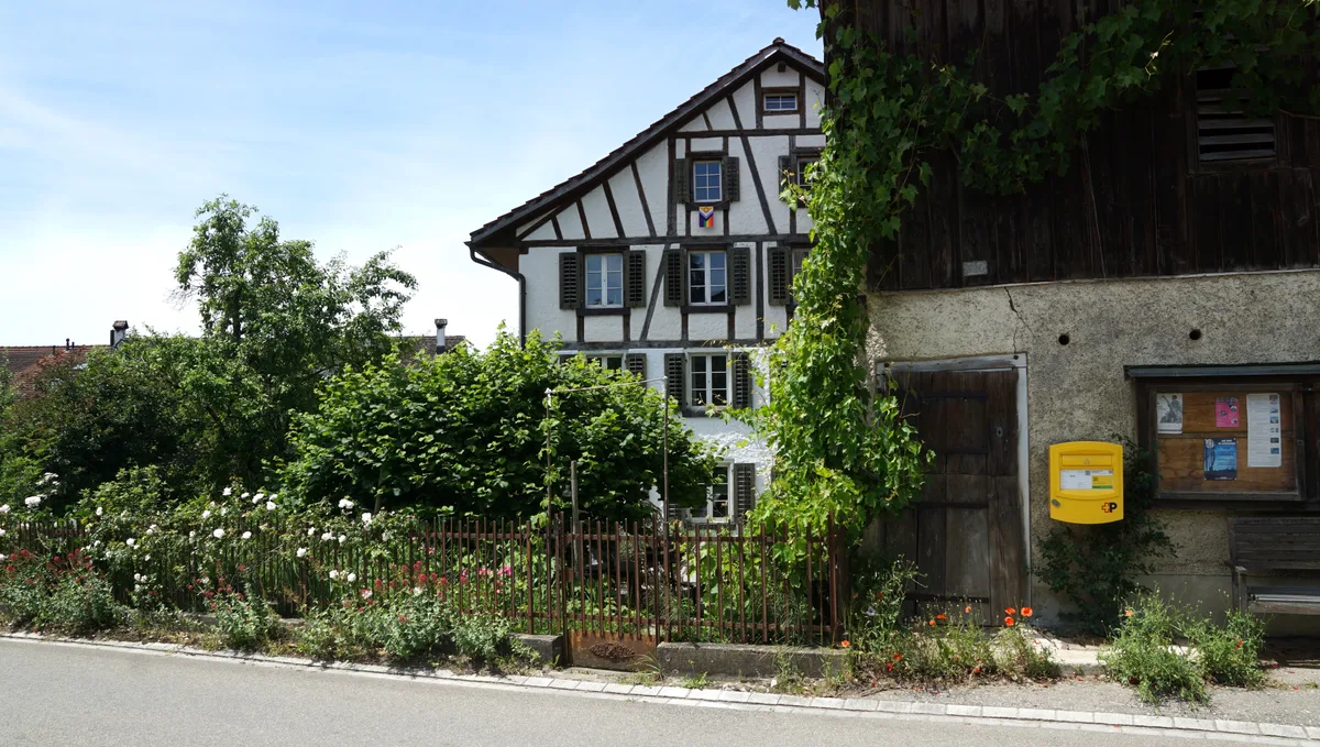 Stall mit dahinterliegendem Wohnhaus und Briefkasten