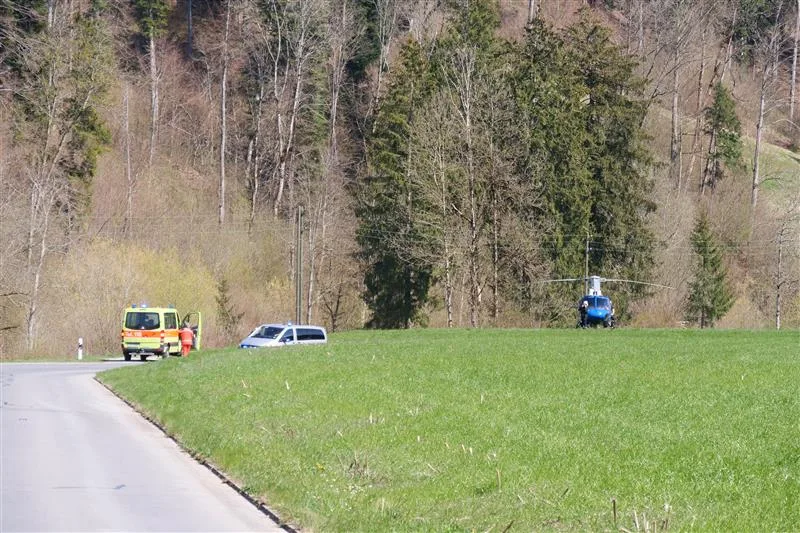 Man sieht ein Feuerwehr-Einsatzfahrzeug und einen geparkten Hubschrauber.