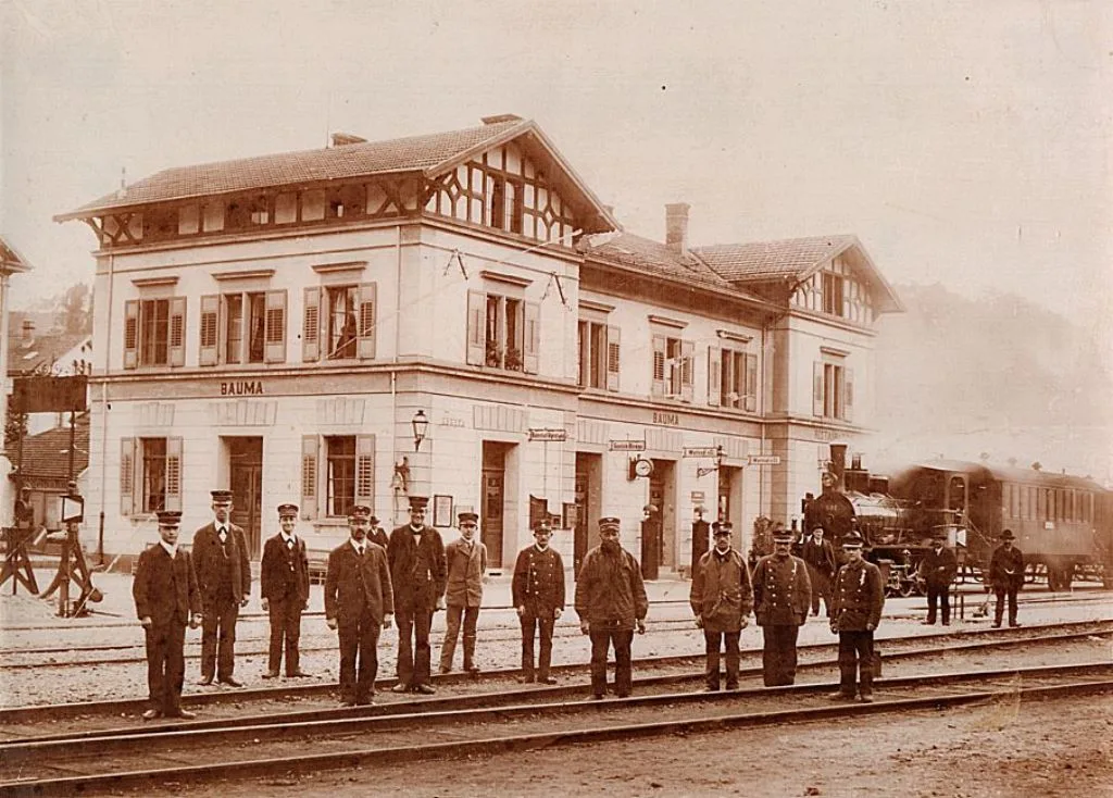 Man sieht Bahnangestellte an einem Bahnhof.