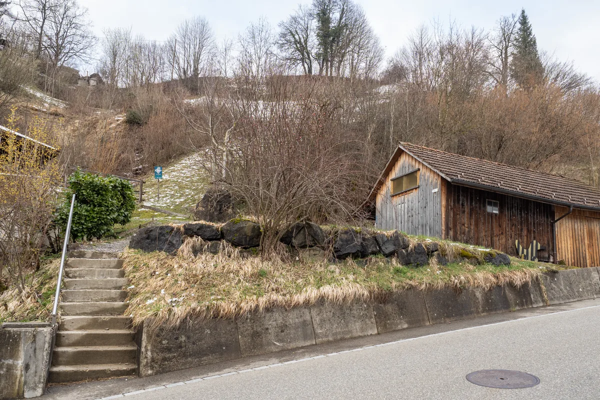 Hier, Höhe Sternenbergstrasse 37, endet für die Fussgänger von Hörnen der Weg. Man sieht eine Treppe, die von einer Strasse wegführt. Daneben steht ein Holzschopf.