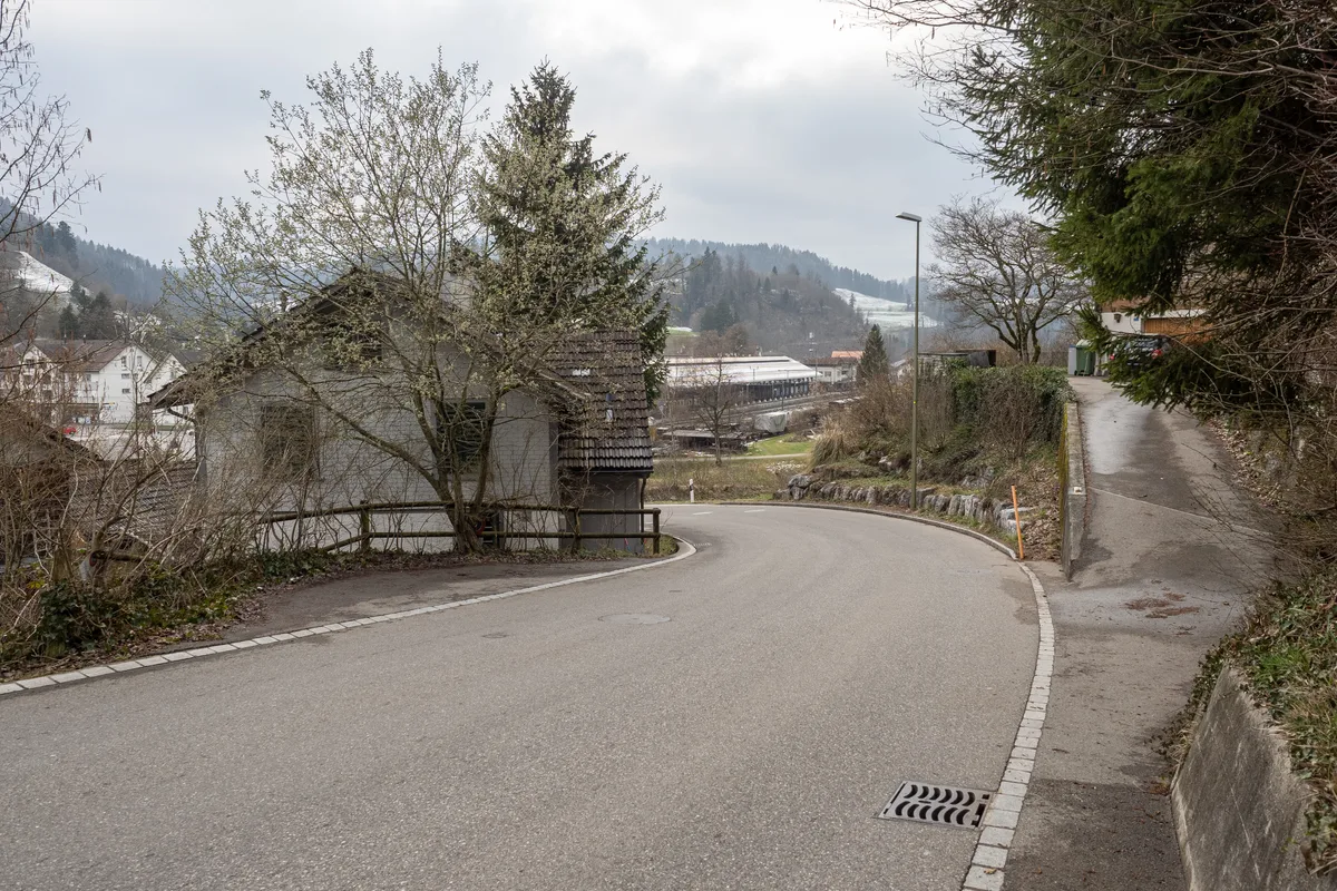 Man sieht eine Strasse, links am Rand steht ein Haus.