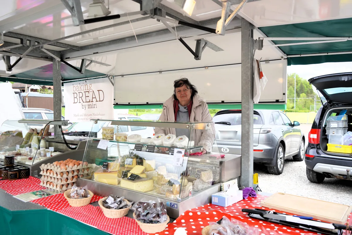 Andrea Pfenninger hat sich für die Weiterführung des Markts in Bauma ins Zeug gelegt – mit Erfolg. Man sieht eine Frau an einem Marktstand mit Fleisch und Käse.