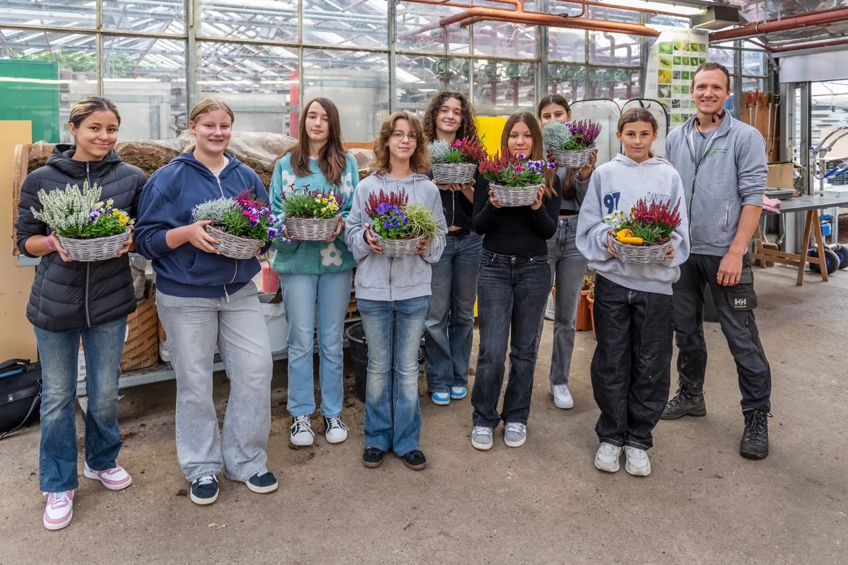 Man sieht eine Gruppe Menschen, von denen jeder einen Blumenkorb hält. 