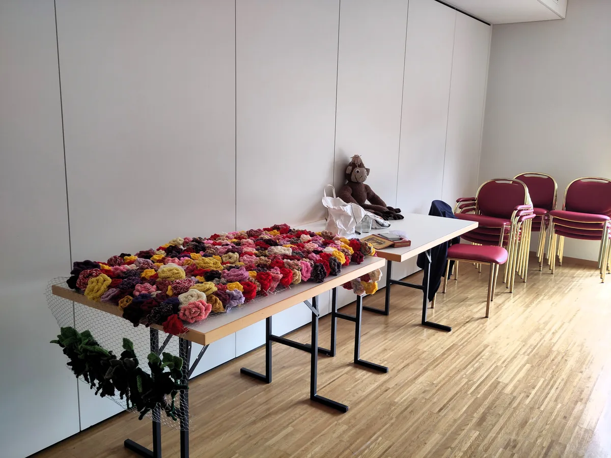Fürs grosse Fest wird fleissig gestrickt. In der Blumenau natürlich Blumen. Man sieht einen Tisch mit gestrickten Blumen.