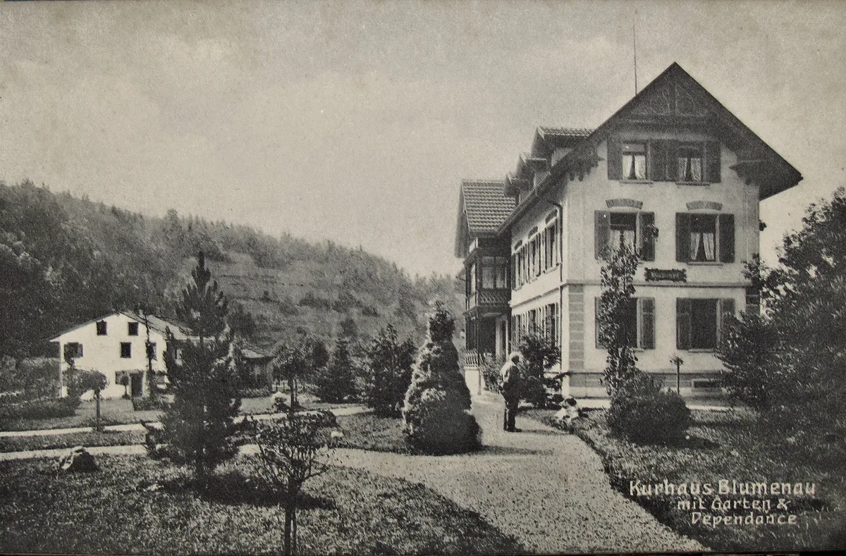 Man sieht eine alte Postkarte mit einem Haus und der Aufschrift Kurhaus Blumenau.
