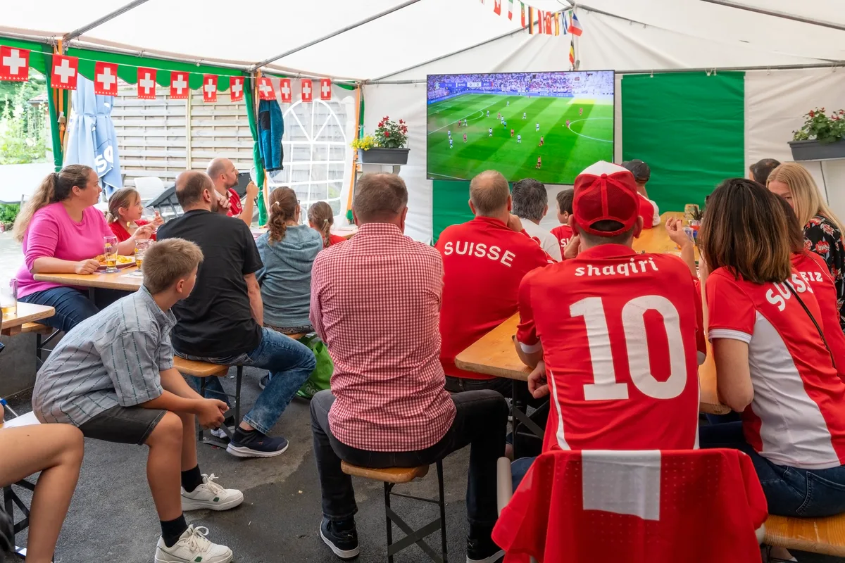 Menschen sitzen und schauen Fussball.