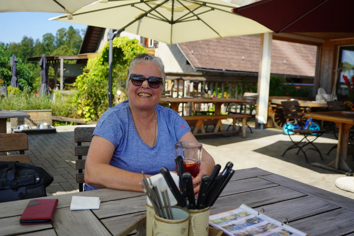Man sieht eine Gästin an einem Tisch draussen.