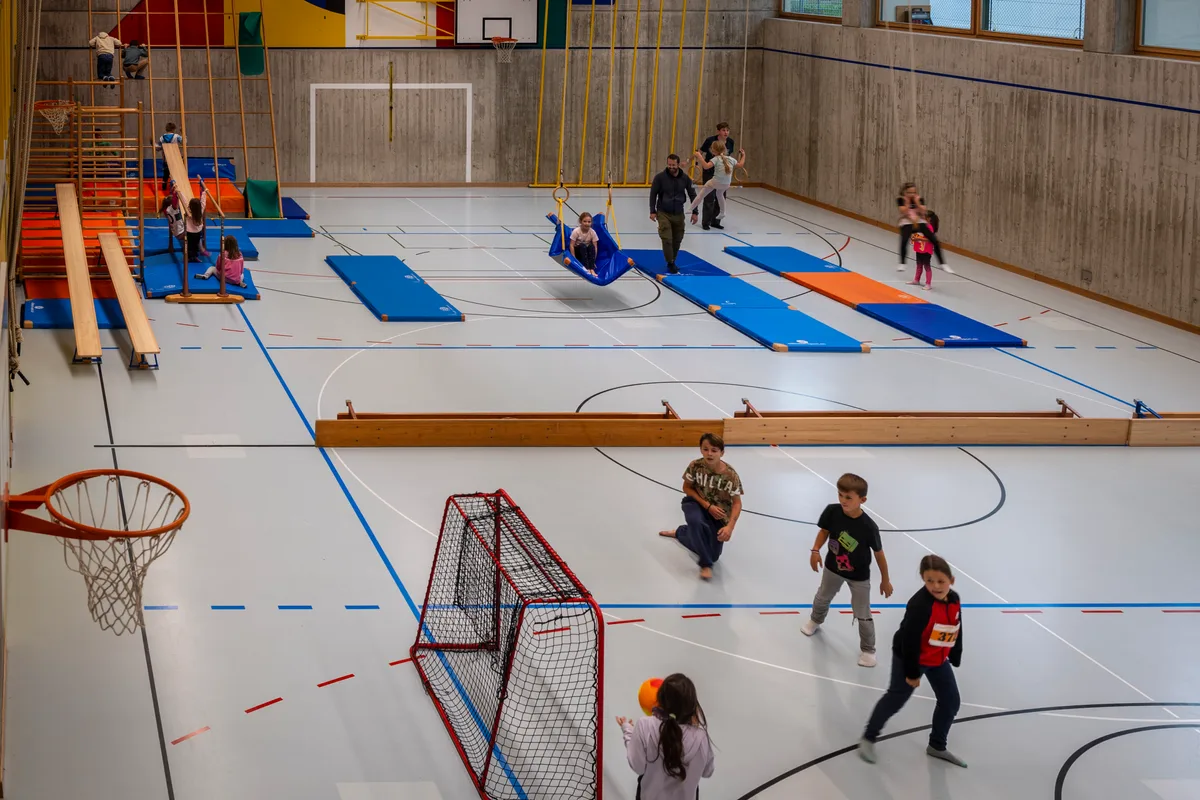 Ganz gemütlich sah es beim Kinderhort in der Turnhalle aus. Hier verbrachten die Kinder einen gemütlichen Nachmittag, während sich ihre Eltern im Regen auf der Strecke abmühten. Kinder sind am Spielen in der Turnhalle.