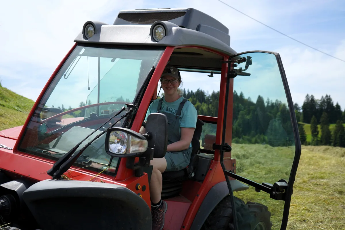 Man sieht eine Frau auf einem Traktor.