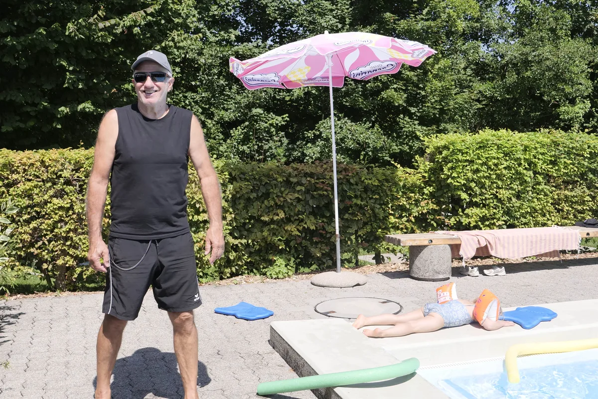 Man sieht einen Bademeister neben einem Schwimmbad.