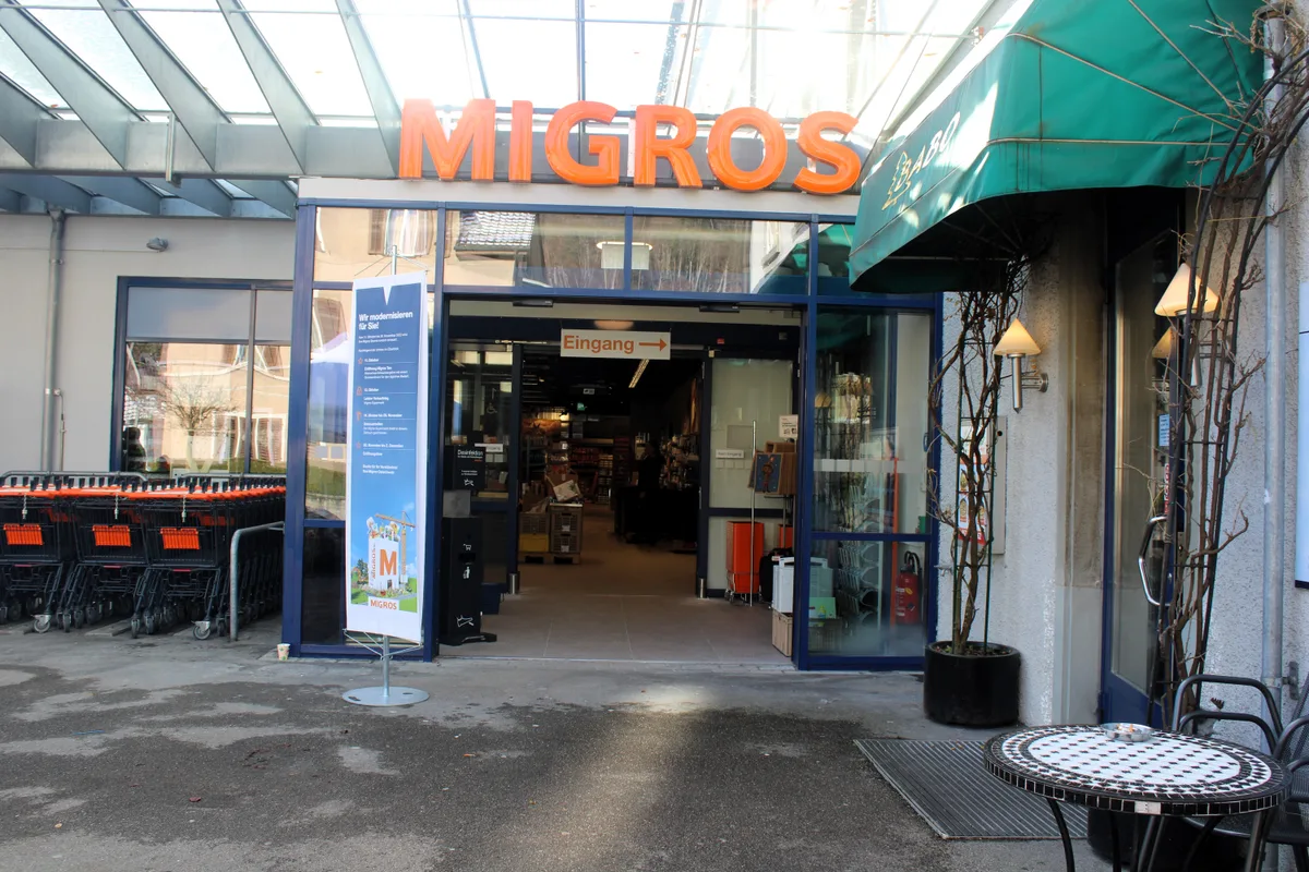 Eingang einer Migros-Filiale mit Wägeli