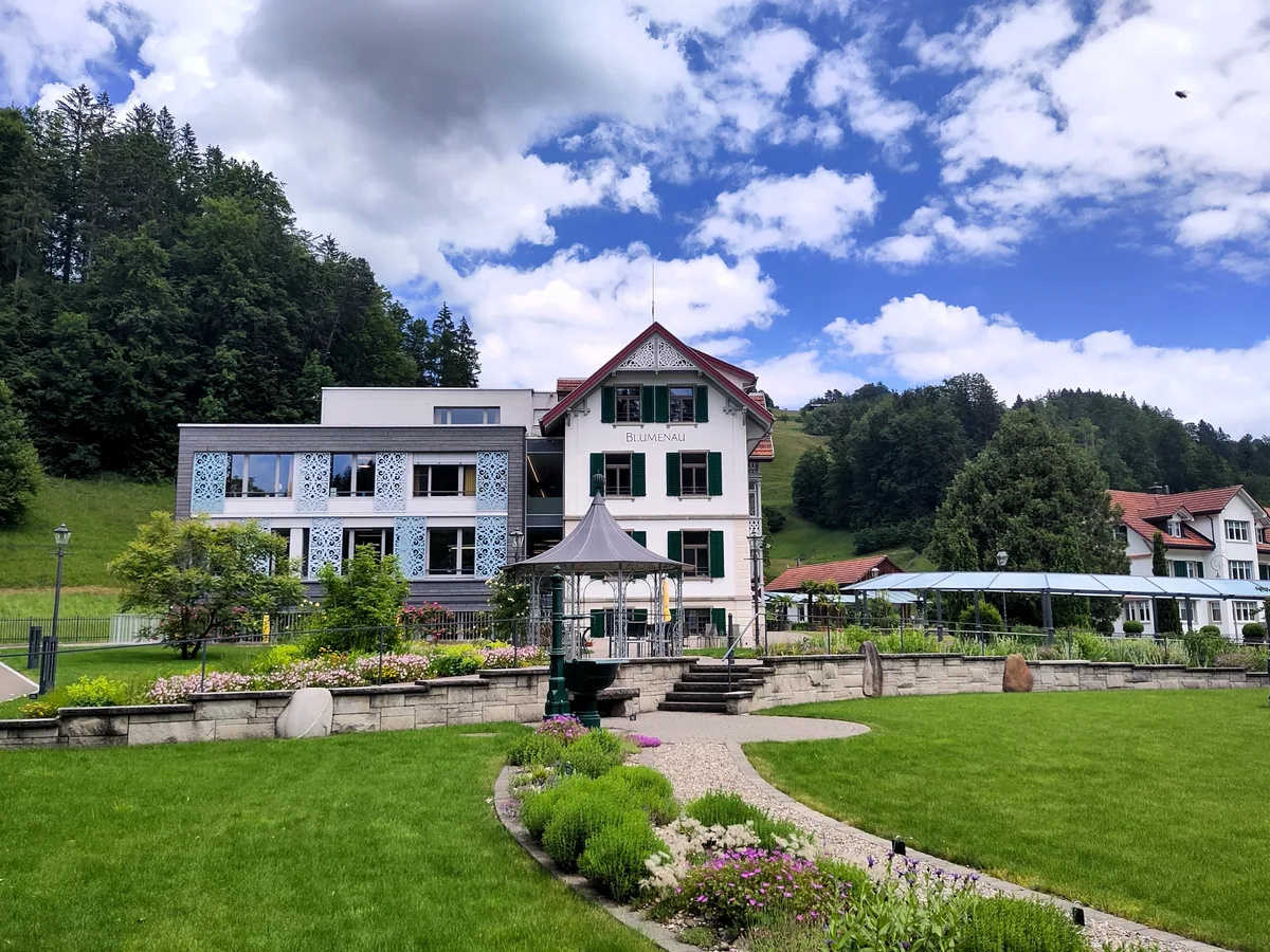 Man sieht ein Gebäude und einen grossen Garten.