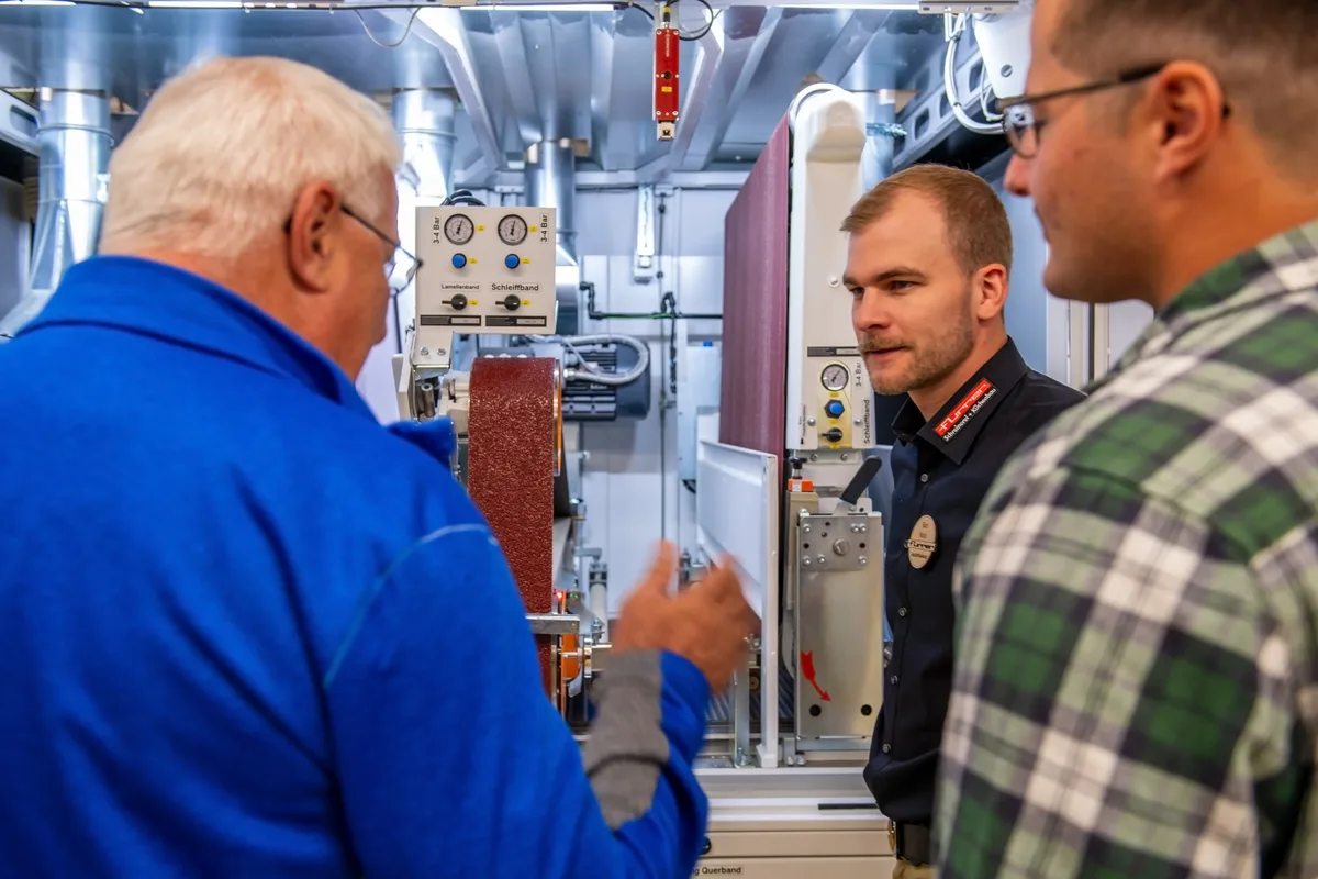 Rico Nock, einer der beiden neuen Geschäftsführer, erklärt die Breitbandschleifmaschine, die mit dem Breitband in der Telekommunikation rein gar nichts gemein hat. Grosser Besucherandrang in der Schreinerei Furrer in Wila.