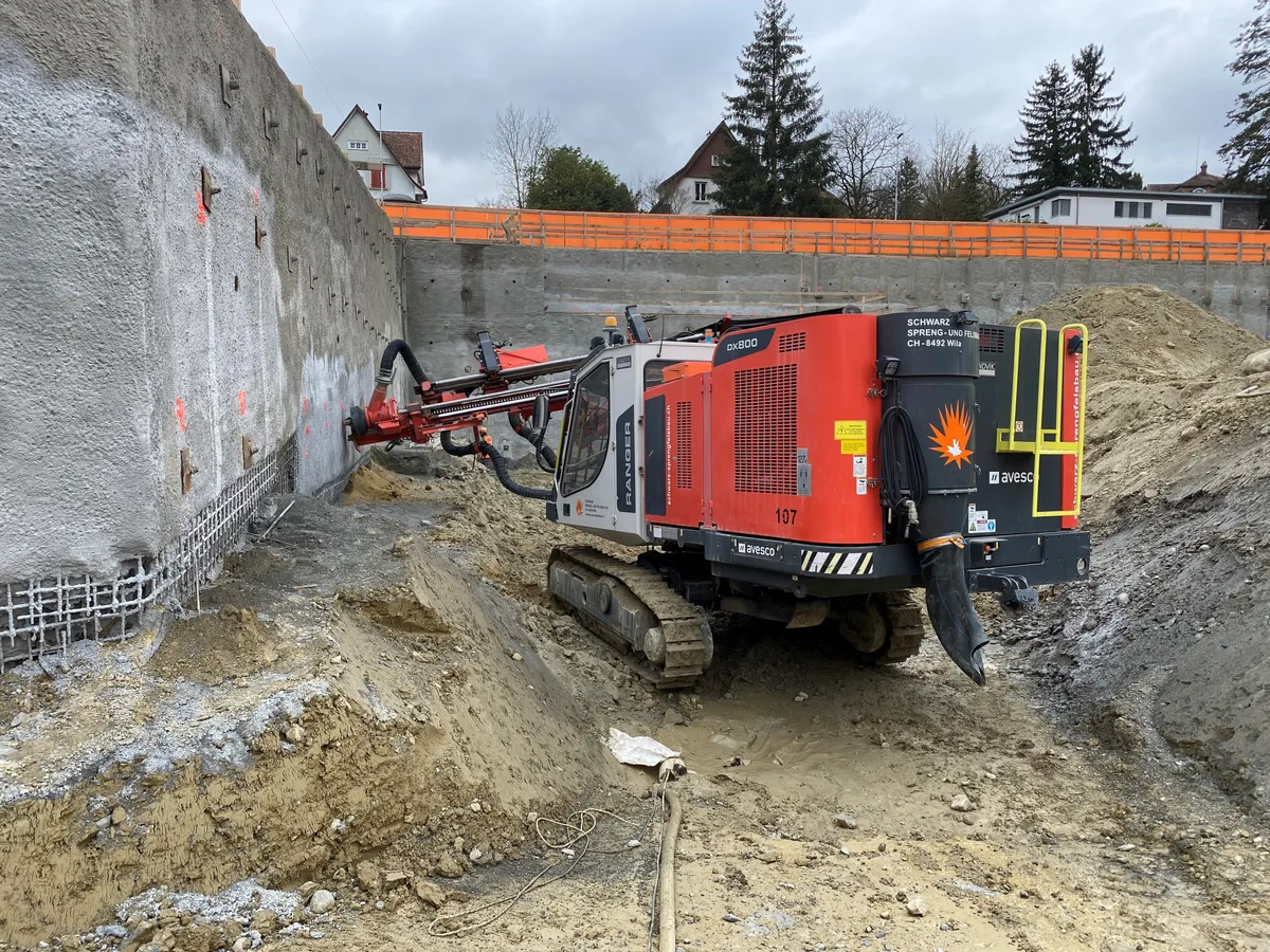 Für die Sprengungsvorbereiten auf Baustellen setzt das Unternehmen oft dieses Bohrgerät ein. Man sieht ein grosses Bohrgerät auf einer Bausstelle