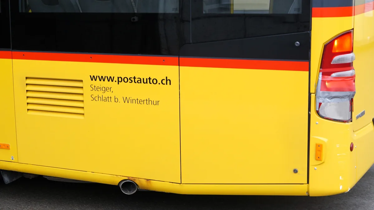 Man sieht eine Beschriftung am Postauto.