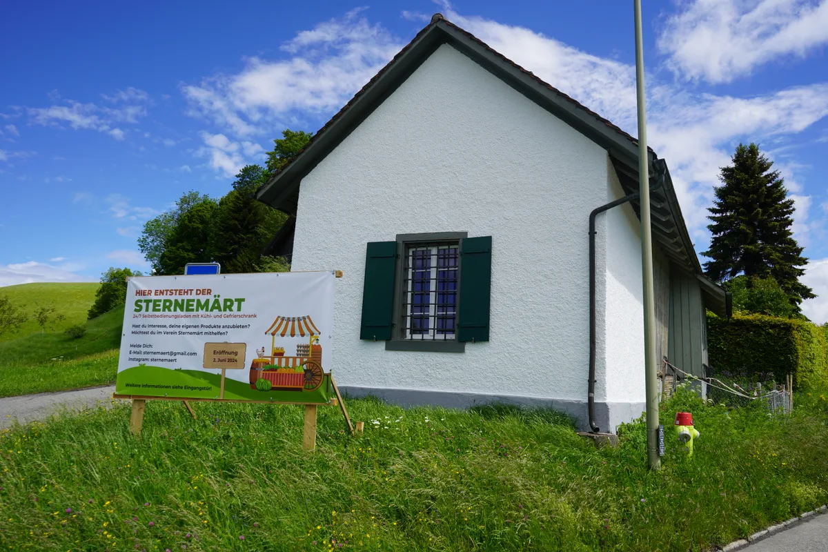Man sieht ein weisses Häuschen und davor ein Plakat mit der Aufschrift «Sternemärt».