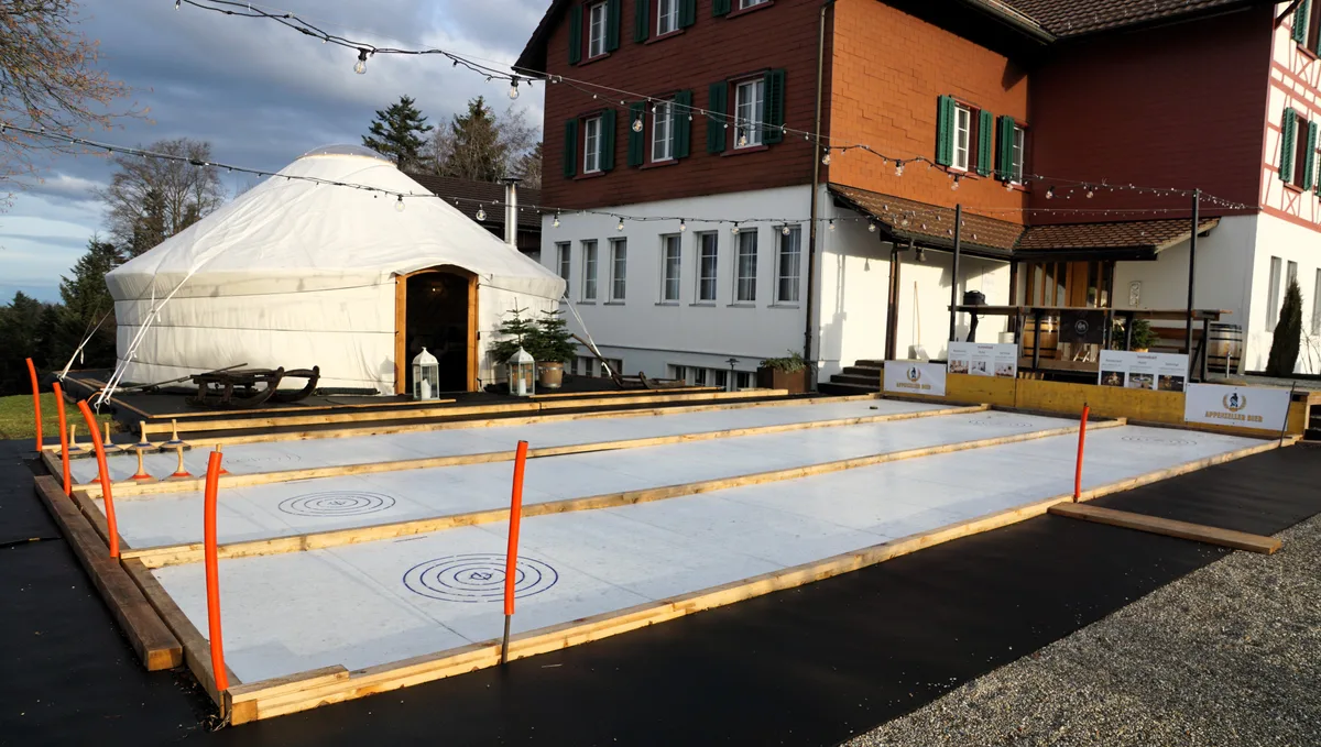 Man sieht drei Eisstockbahnen und eine Jurte.