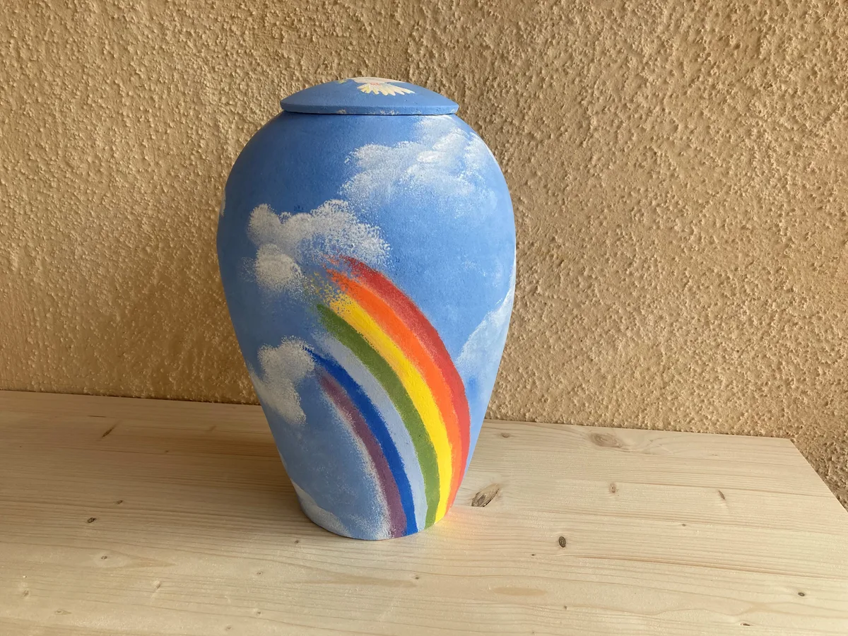 Ihre Urnen sollen ein Andenken an einen verstorbenen Menschen darstellen. Man sieht eine Urne mit Regenbogen.