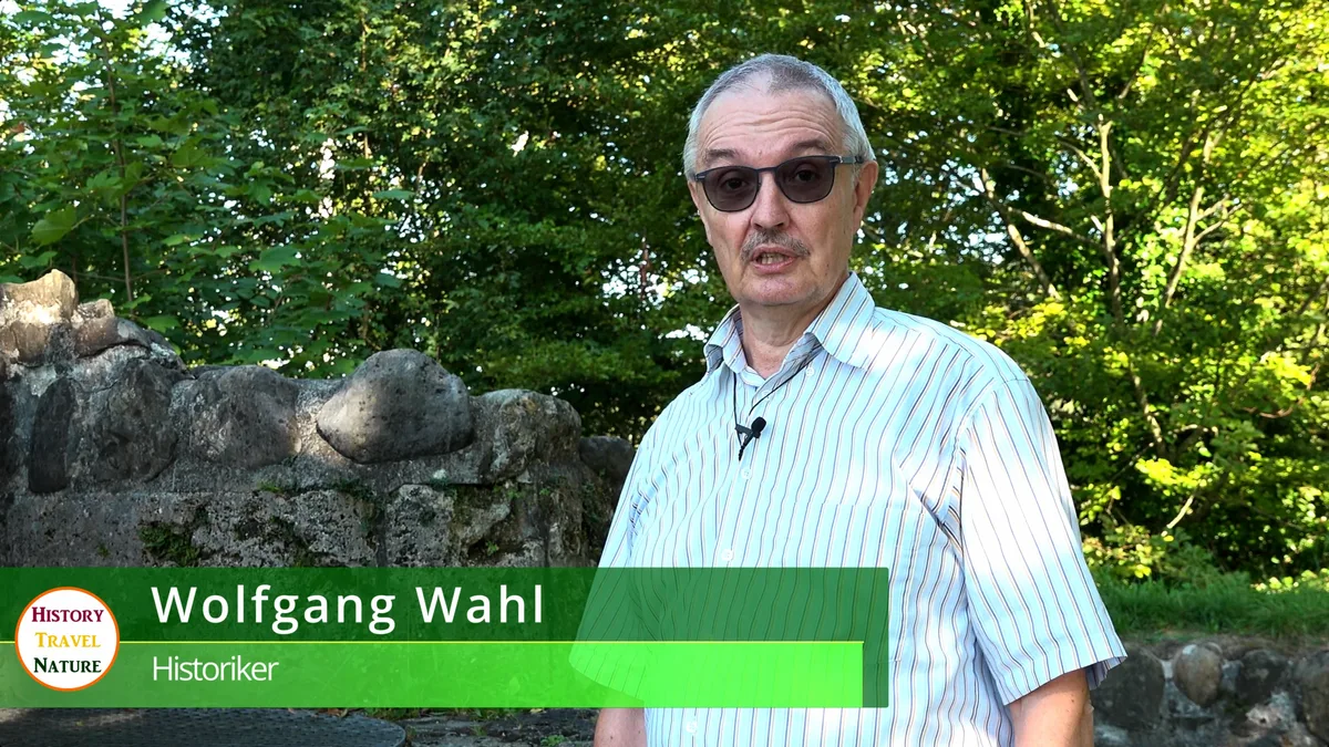 Man sieht einen älteren Mann bei einem Interview auf einer Burgruine.