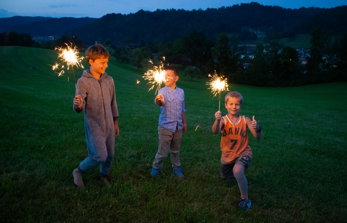 Man sieht drei Kinder mit Wunderkerzli.
