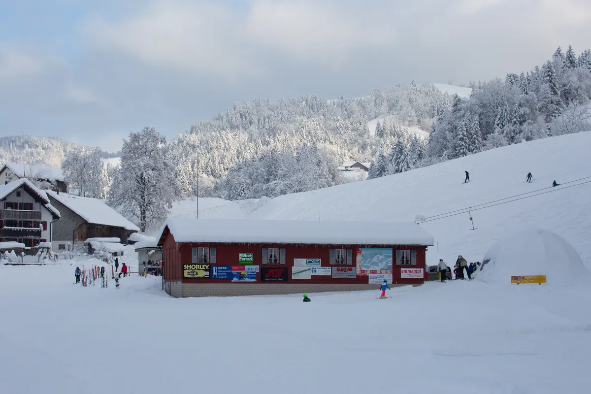 Mehrere Hütten und Häuser, eine Skipiste und ein Skilift.