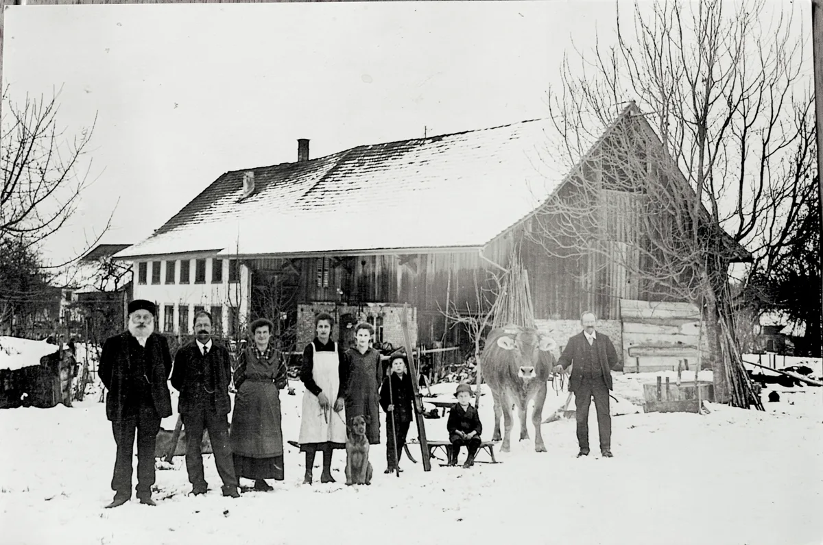 Der «Obstgarten» zirka 1920. Der Bub neben dem Schlitten ist der Vater von Hedi Werren. Der Mann rechts bei der Kuh ist der Knecht. Man sieht eine Familie mit Kuh im Schnee.