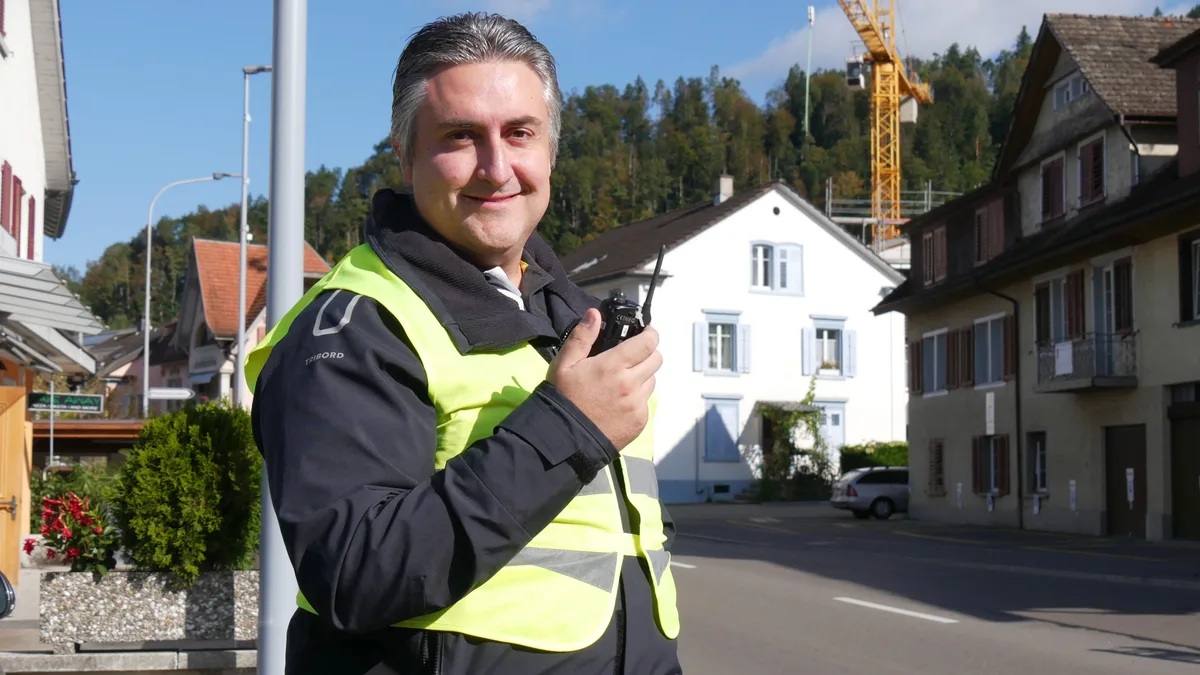 Porträtbild eines Herrn mit Leuchtweste und Funkgerät.