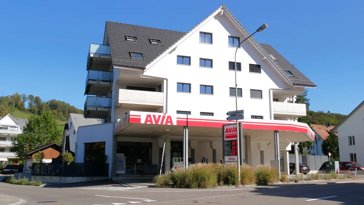 Aussenansicht einer Tankstelle, die Teil eines Mehrfamilienhauses ist.