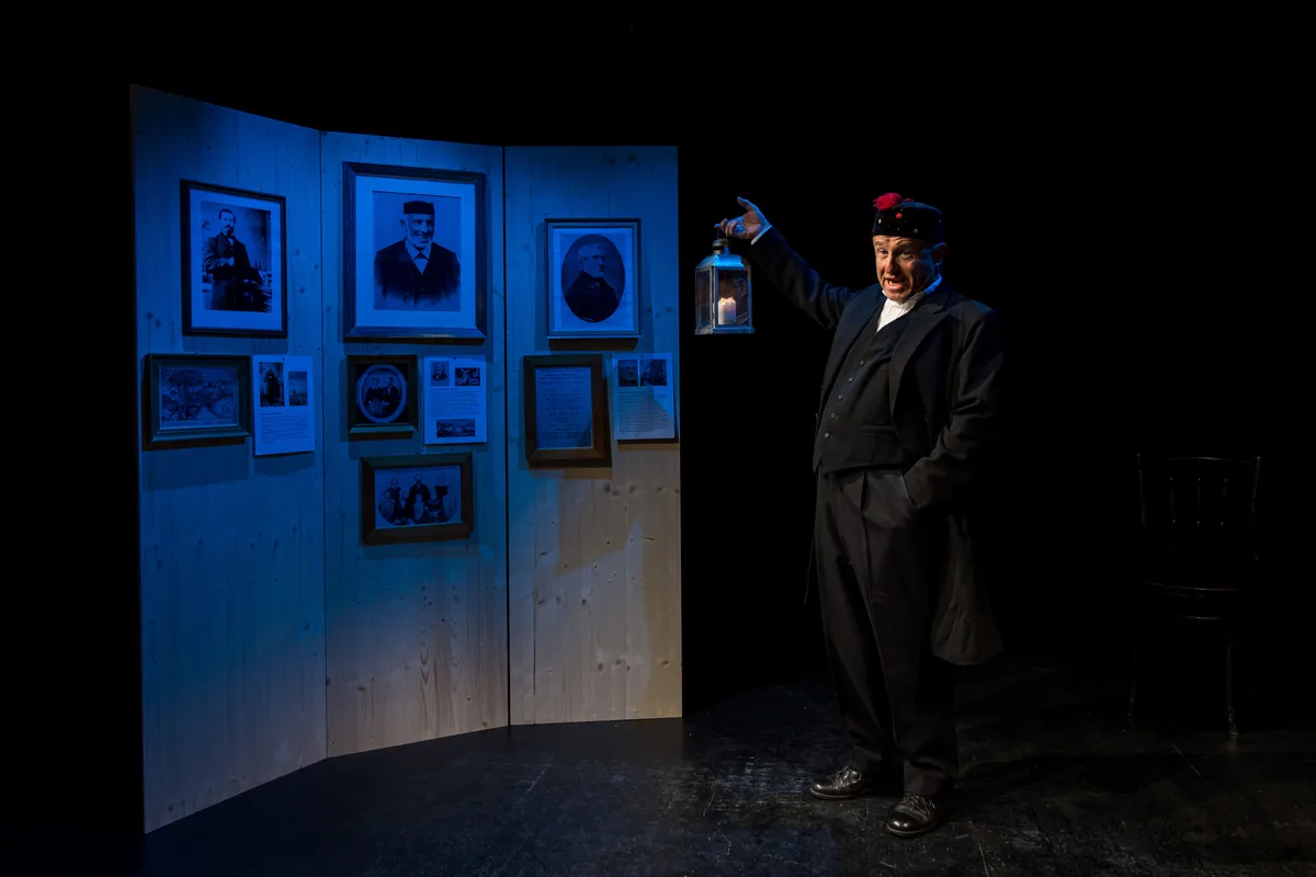 Auf der Bühne spricht Keller auch zu Jakob Senn und Johannes Schoch – oder zumindest ihren Porträts. Man sieht einen Mann auf einer Bühne in einem Theaterstück. Hinter ihm sieht meine eine Wand mit Porträts.
