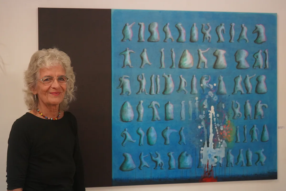Frau steht vor blauem Kunstwerk.